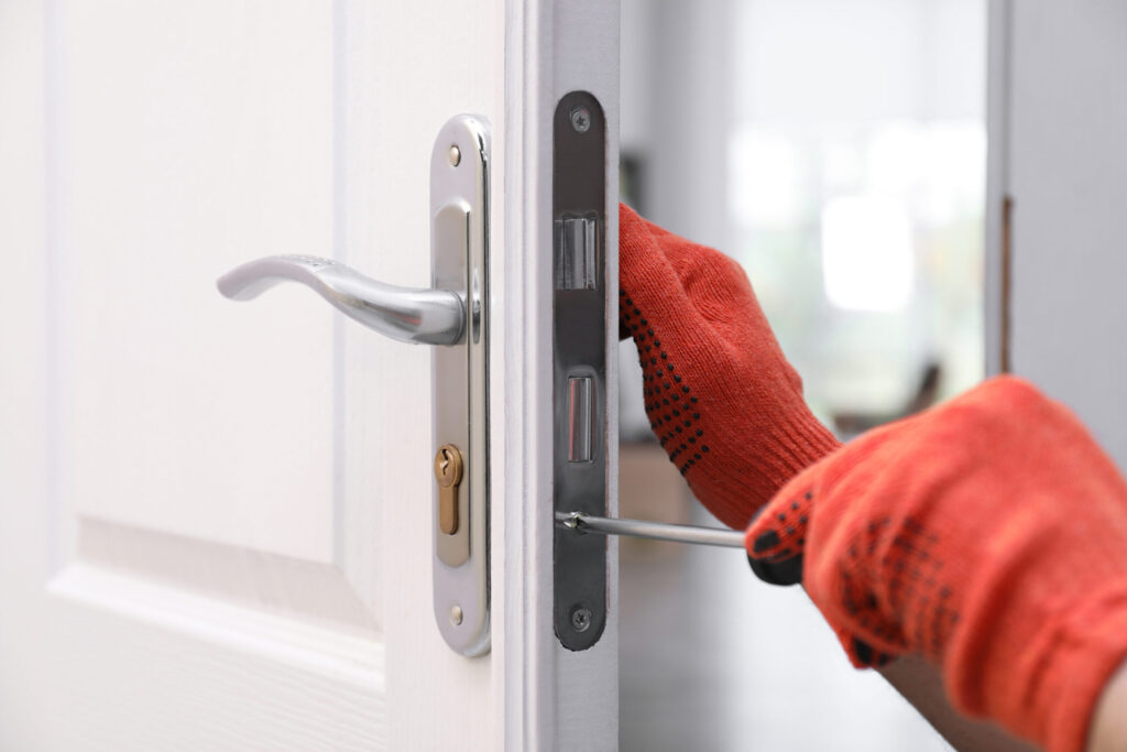 A professional locksmith rekeying a front door lock after a homeowner has moved in.